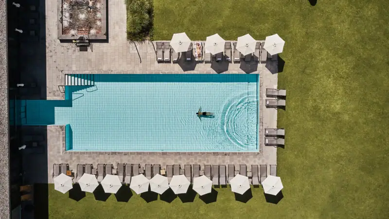 Zwembad van bovenaf Zwembad met parasols en ligweide.