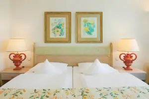 Junior suite met uitzicht op het meer en balkon Een bed met twee lampen en twee foto's aan de muur.