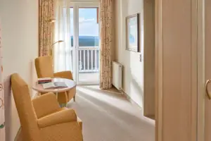 Junior suite met uitzicht op het meer en balkon Een kamer met een tafel en stoelen.