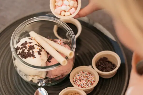 IJs bij aja Garmisch-Partenkirchen Een kind strooit marshmallows op een ijscoupe bij aja Garmisch-Partenkirchen.