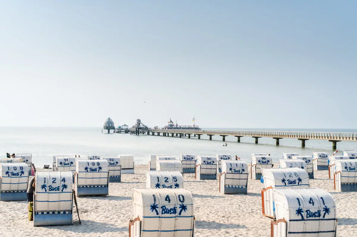 Een strand met witte stoelen en blauwe strepen.