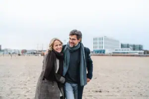 Een man en een vrouw lopen over het strand.