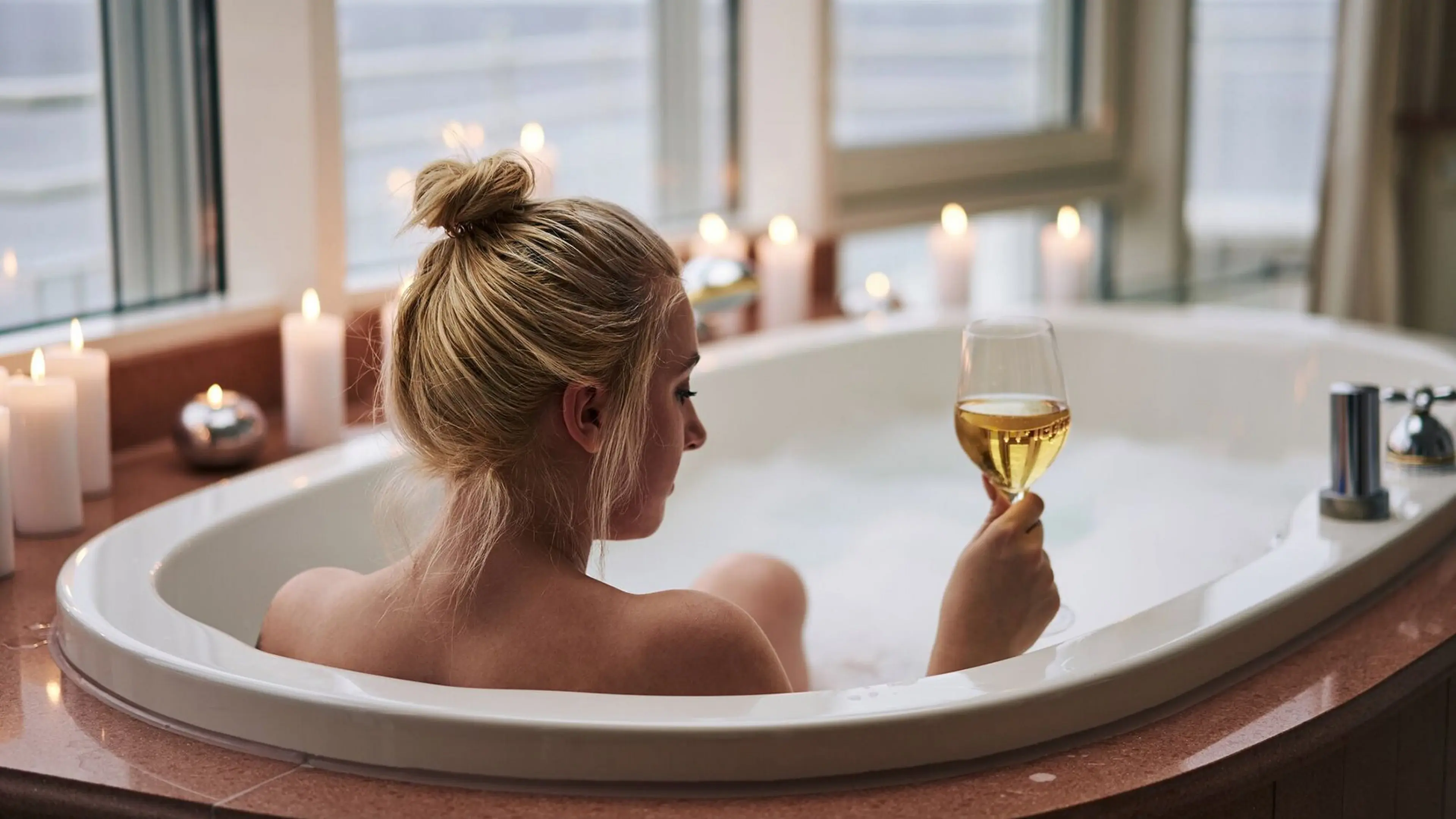Badewanne Eine Frau in einer Badewanne hält ein Glas Wein.