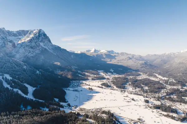 Garmisch-Partenkirchen Verschneite Berglandschaft mit einer Stadt und Bäumen.