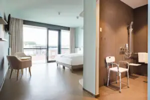 Mindervalide kamer Een kamer met een bed en stoelen.