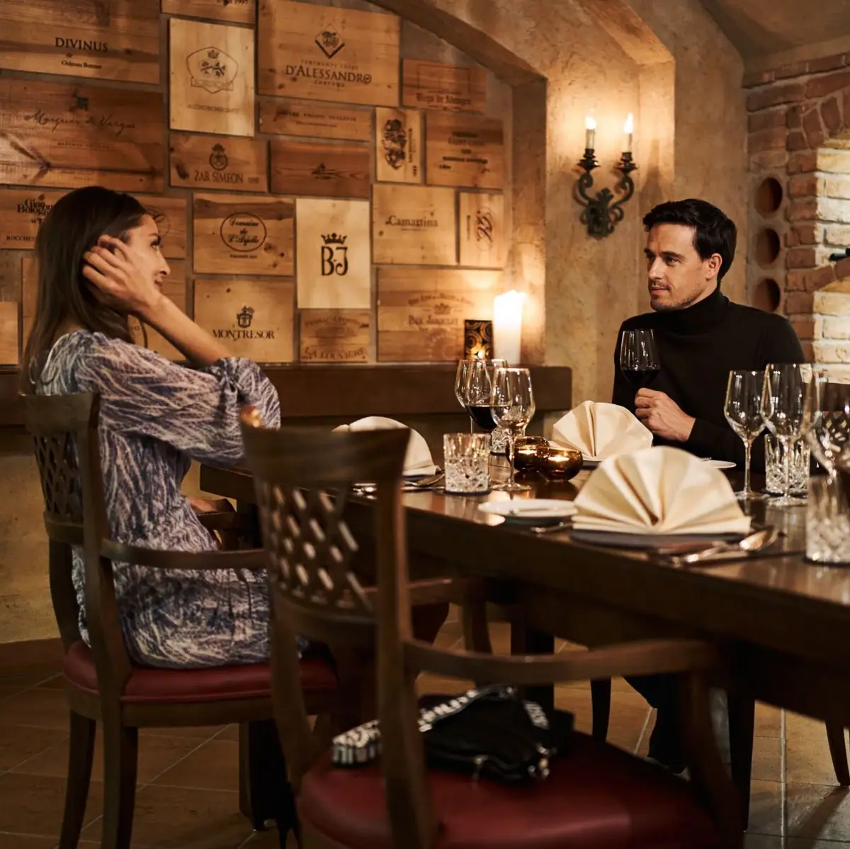 Een man en een vrouw zitten aan een tafel met glazen wijn.