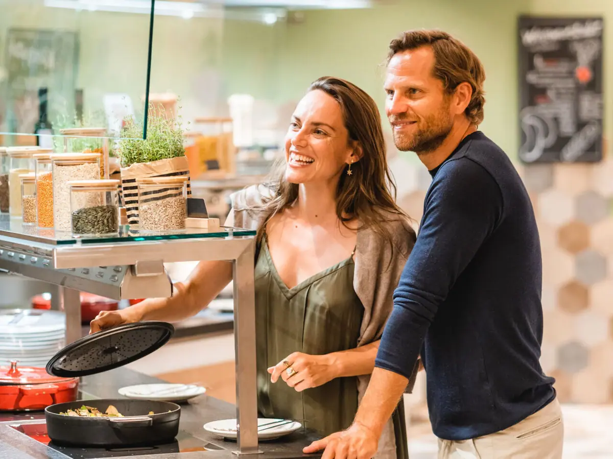 Een man en een vrouw staan naast een toonbank met eten.