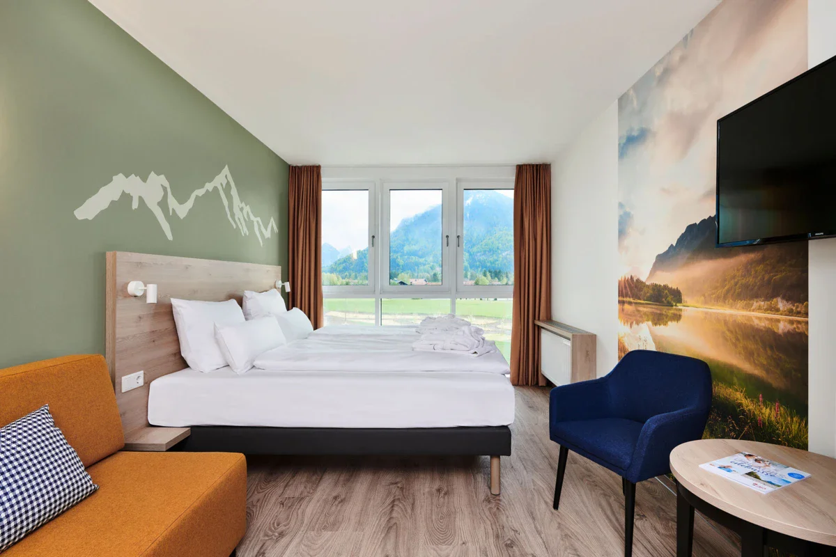 Een kamer met een bed en stoelen in het aja Hotel Ruhpolding.