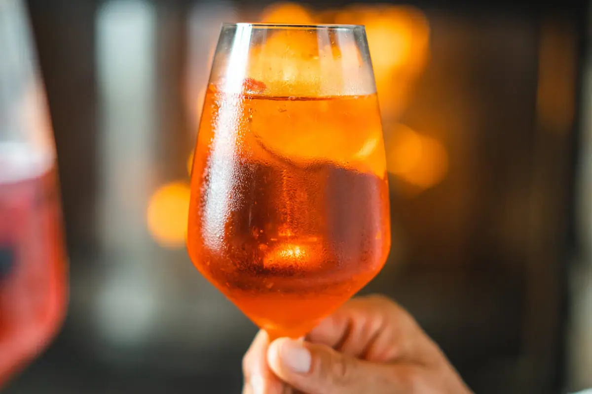Aperol Een hand houdt een glas met oranje drank vast.