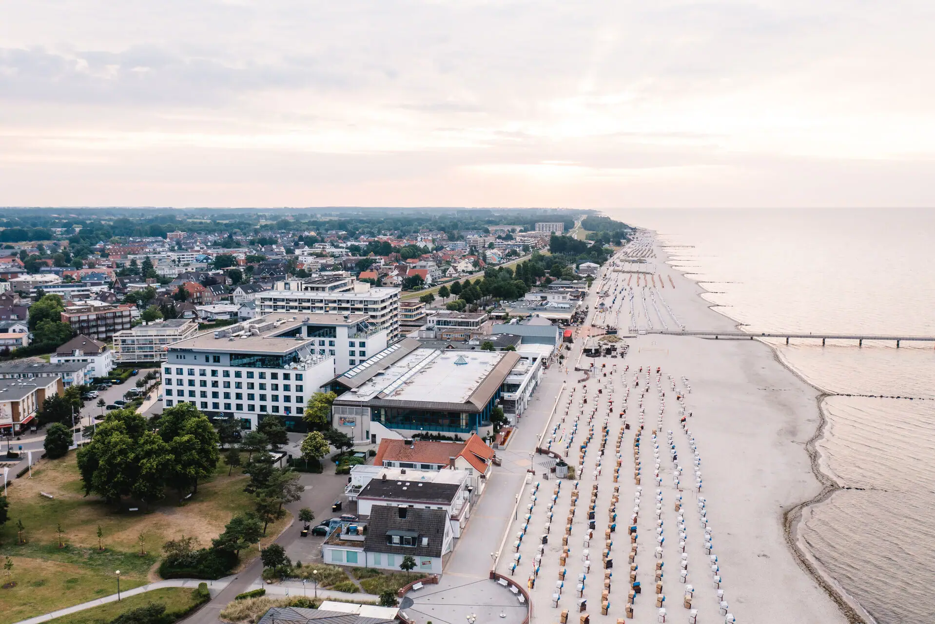 Vogelperspectief van het strand met veel strandstoelen en gebouwen.
