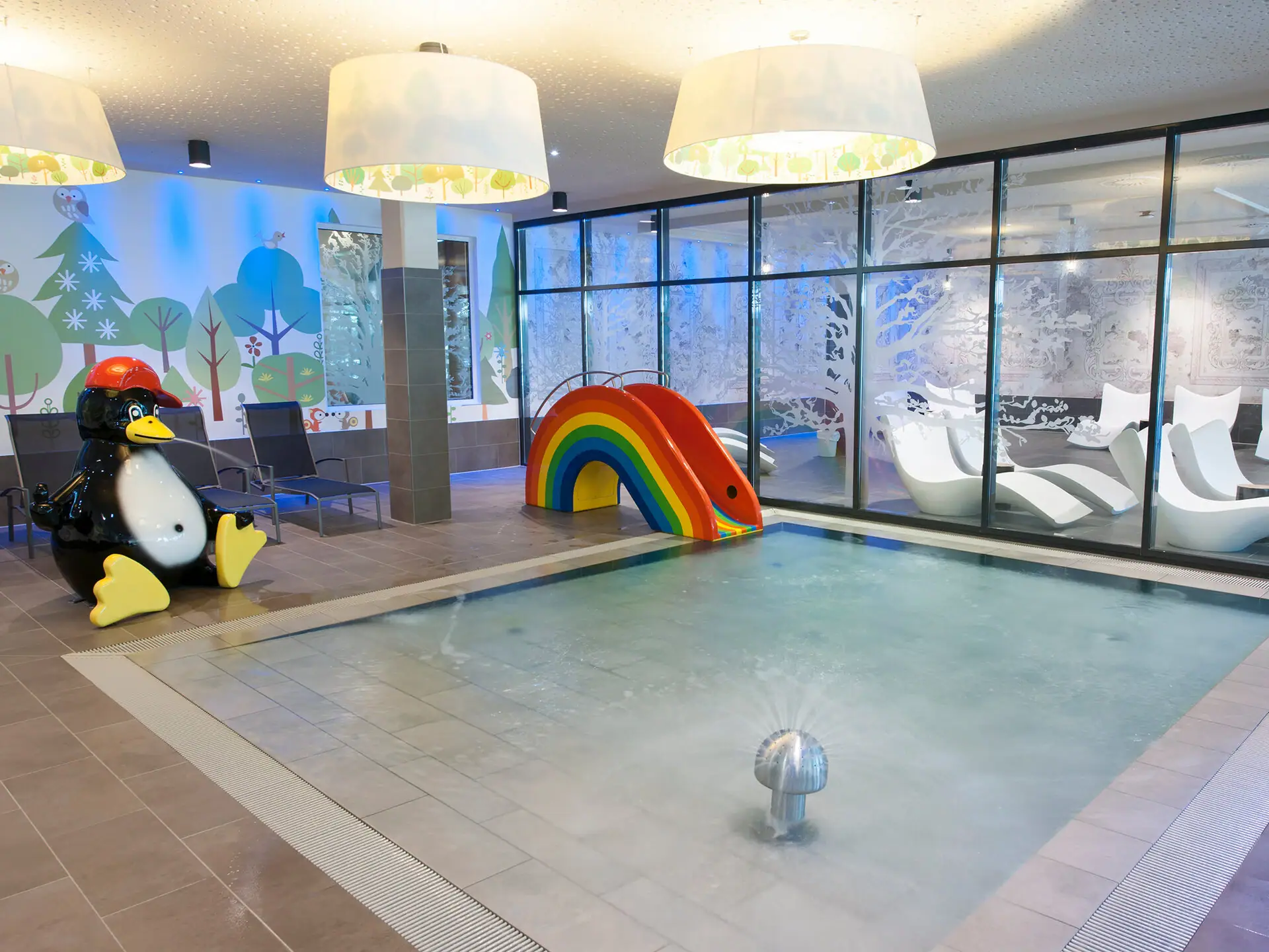 Kinderzwembad bij aja Bad Saarow Een zwembad met een glijbaan en een pinguïn.