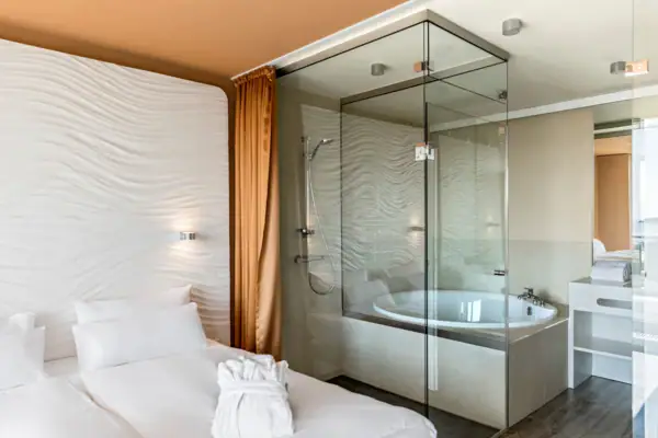 Badkamer met glazen douche en bed