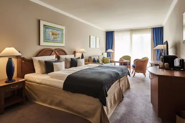 Zimmer aja Bansin Hotelzimmer mit Bett und Stühlen, stilvoll eingerichtet mit Kissen und Nachttisch.