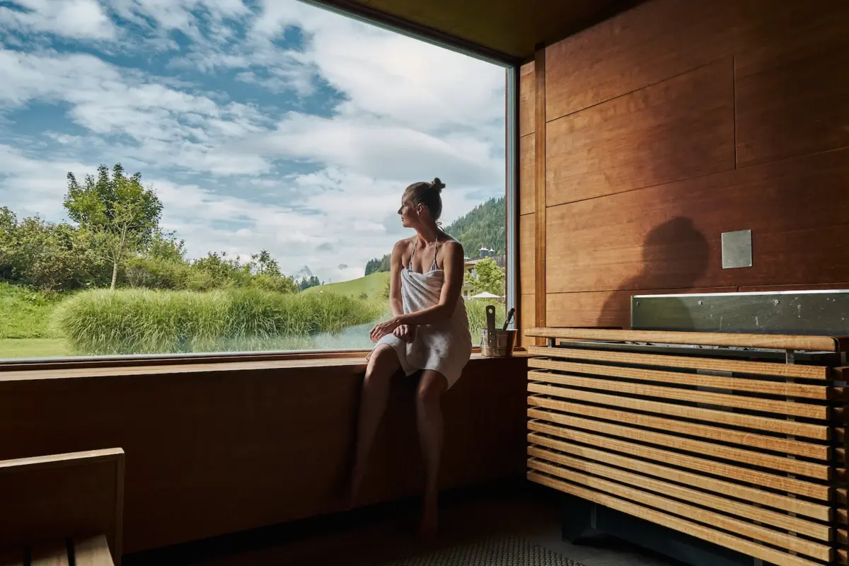 Een vrouw zit op een vensterbank en kijkt uit het raam.