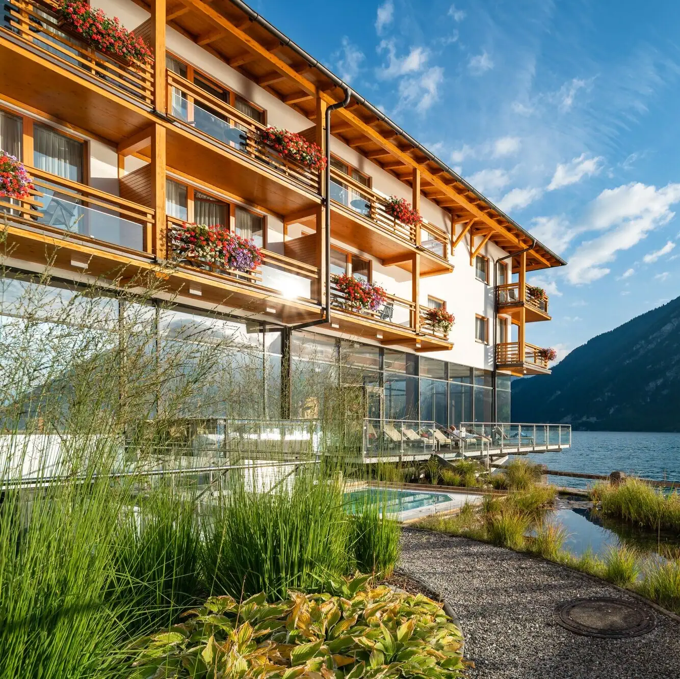 Vorstelijk huis aan het Achenmeer Een gebouw met een meer en bergen op de achtergrond.