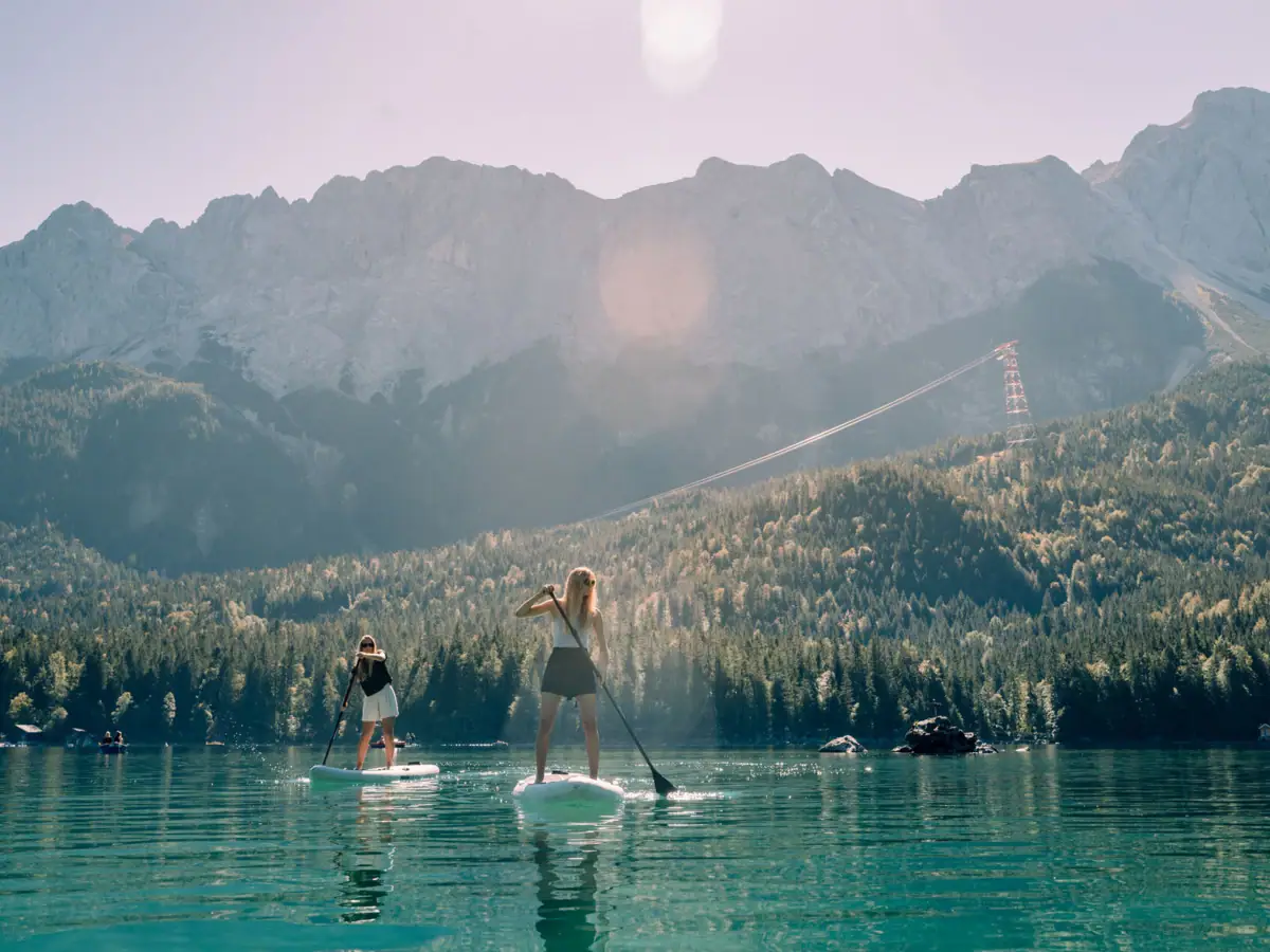 SUP Eibsee Vrouwen op paddleboards op een meer met bergen op de achtergrond.