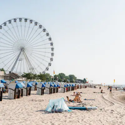 Activiteiten in Grömitz Een strand met een reuzenrad en mensen erop.