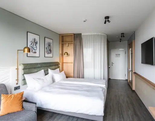 Nieuwe kamers bij aja Warnemünde Hotelkamer met tweepersoonsbed, kussens en beddengoed.