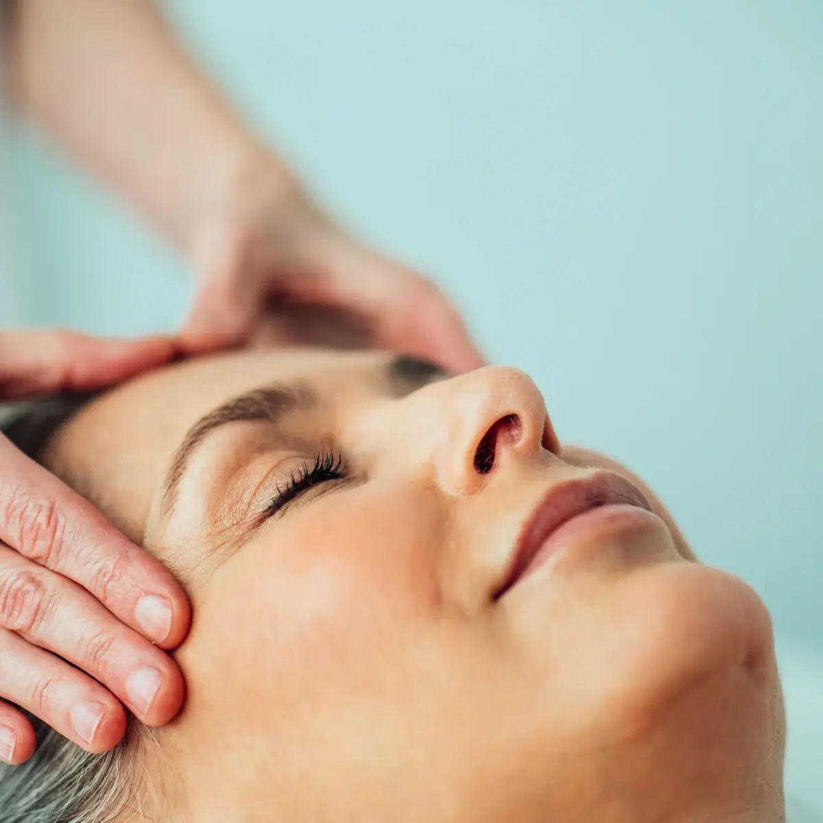 Iemand masseert het hoofd van een vrouw.