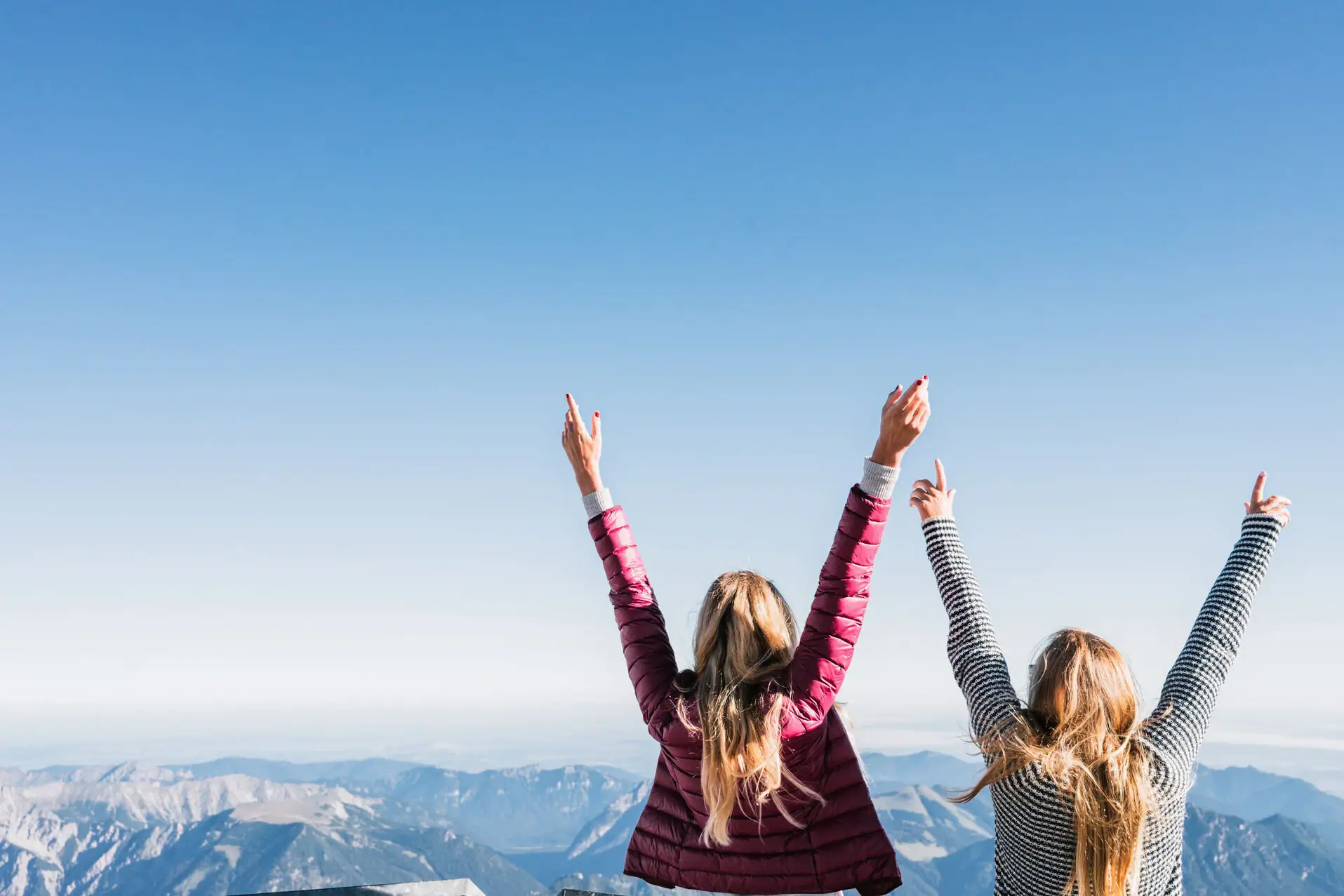 Zugspitze Twee vrouwen staan op een berg met hun armen omhoog.