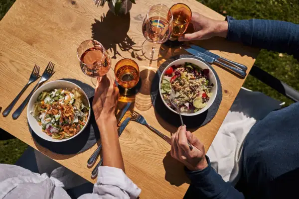 Gastentuin Een groep mensen aan een tafel met eten en drinken.