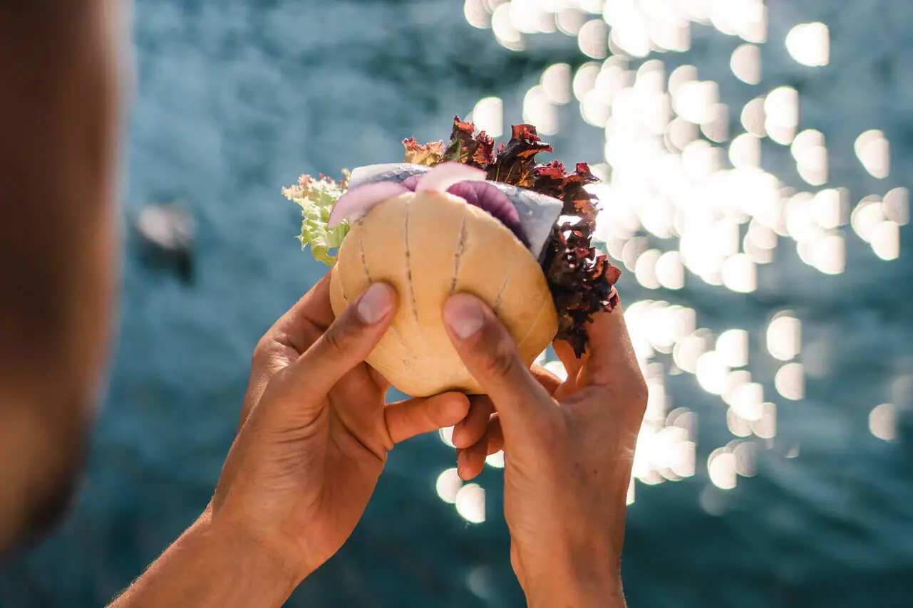 Een persoon houdt een visrol boven water.