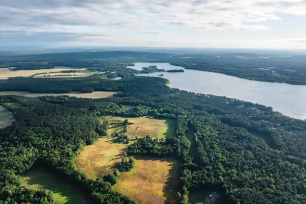 Luchtfoto van het meer en een bos met een akker vanuit vogelperspectief.
