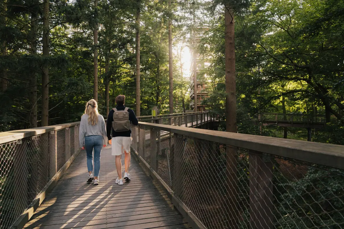Een man en een vrouw lopen over een brug bij de boomtoppenwandeling in Usedom