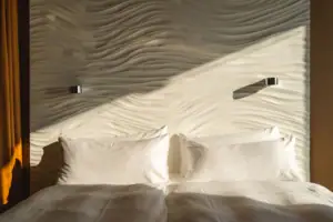 Kamers in het aja Warnemünde Een bed met kussens voor een verlichte muur.