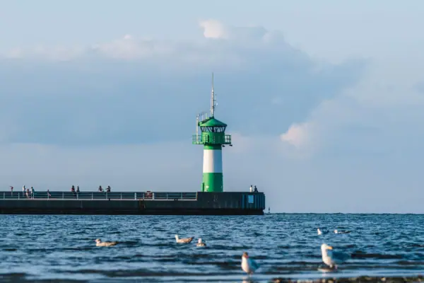 Een vuurtoren op een pier tegen een bewolkte hemel.