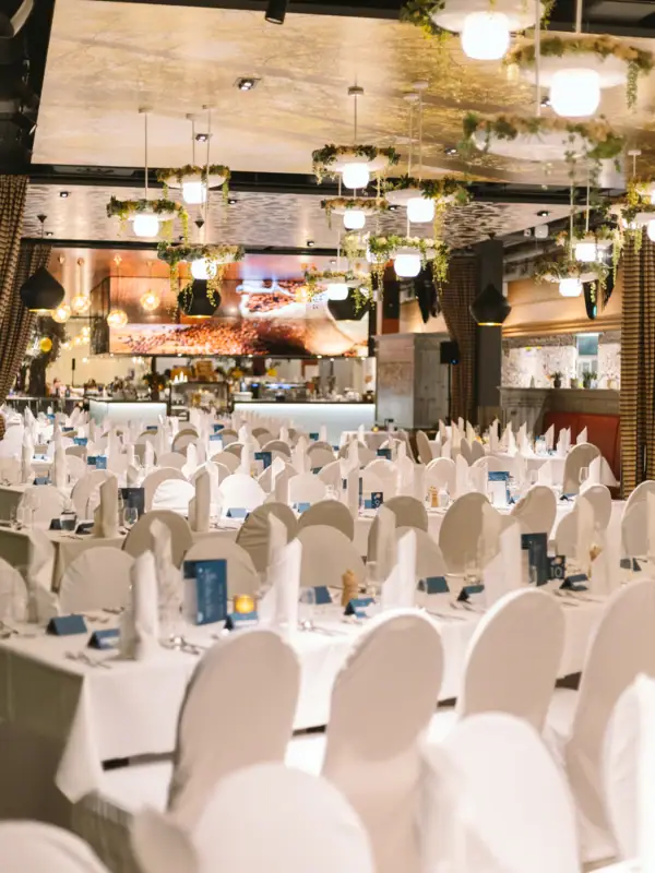 Een kamer met tafels en stoelen, klaar voor een feestje.