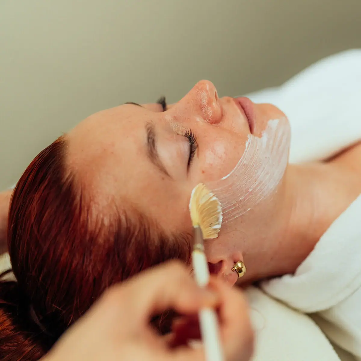 Cosmetica Er ligt een vrouw met een wit masker over haar gezicht.
