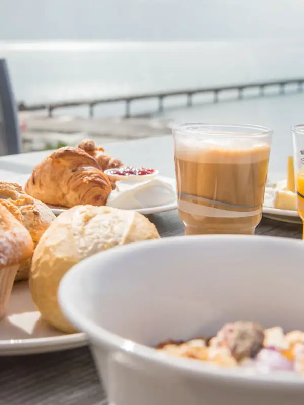 Een tafel met verschillende etenswaren en drankjes, waaronder gebak en kopjes.