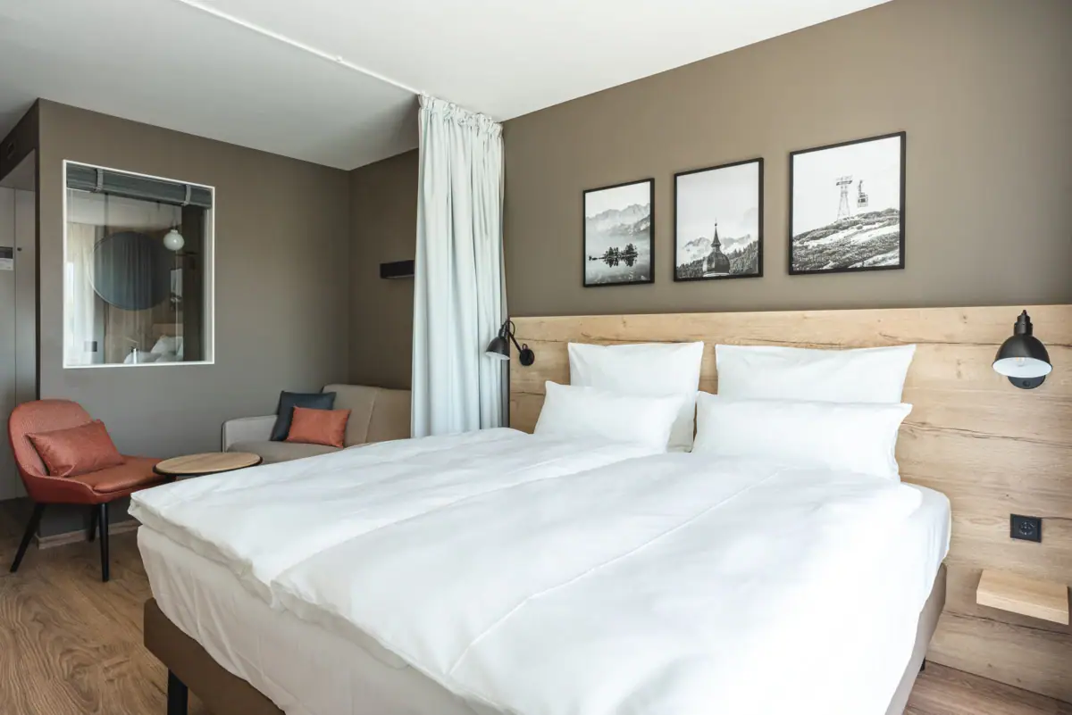 Kamer 118 Een bed met witte lakens en een stoel in de kamer.