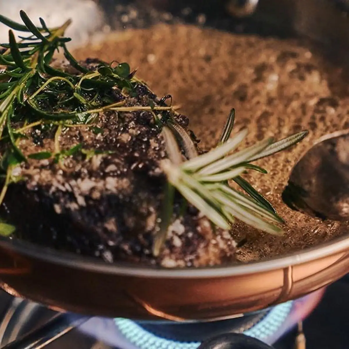 Een pot met een stuk vlees en een lepel.