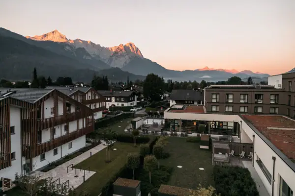 Ausblick Eine Gruppe von Gebäuden mit Bäumen und Bergen im Hintergrund.