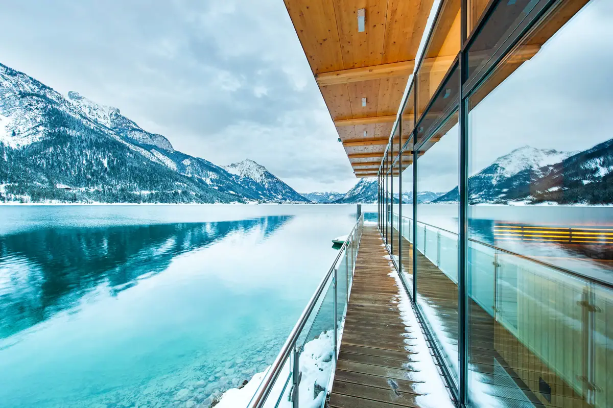 De Achensee in de winter Een glazen wand met een terras en uitzicht op een meer