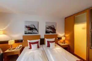 Tweepersoonskamer Een kamer met twee bedden en schilderijen aan de muur.