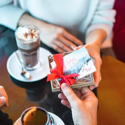 Eén persoon houdt een geschenkdoos met een rood lint vast.