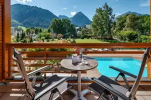 Tweepersoonskamer Een tafel en stoelen op een balkon met uitzicht op een zwembad.