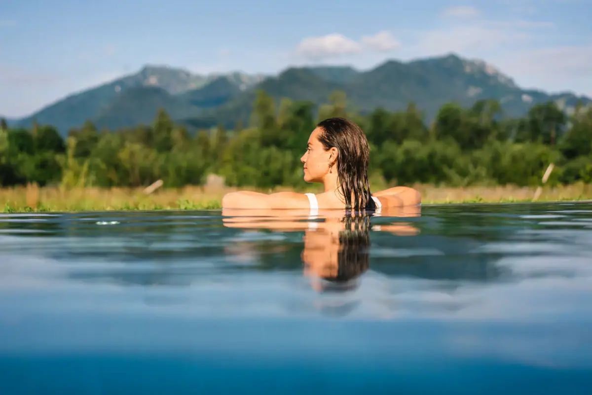 Zwembad in het aja Ruhpolding Een vrouw in een zwembad met bergen op de achtergrond.