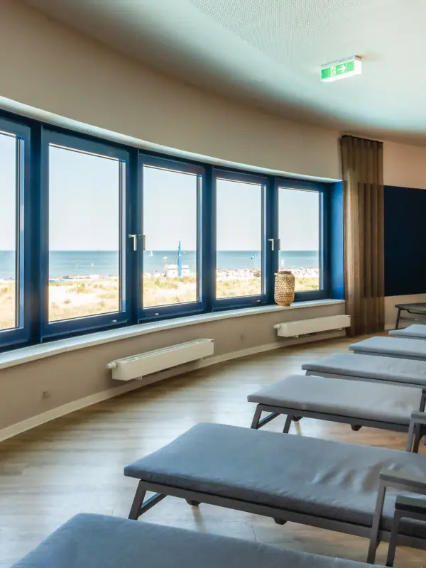 Een kamer met stoelen en grote ramen.