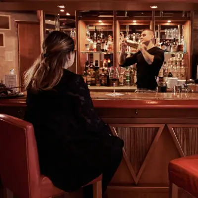 Een man en een vrouw in zwarte jurken zitten aan een bar.