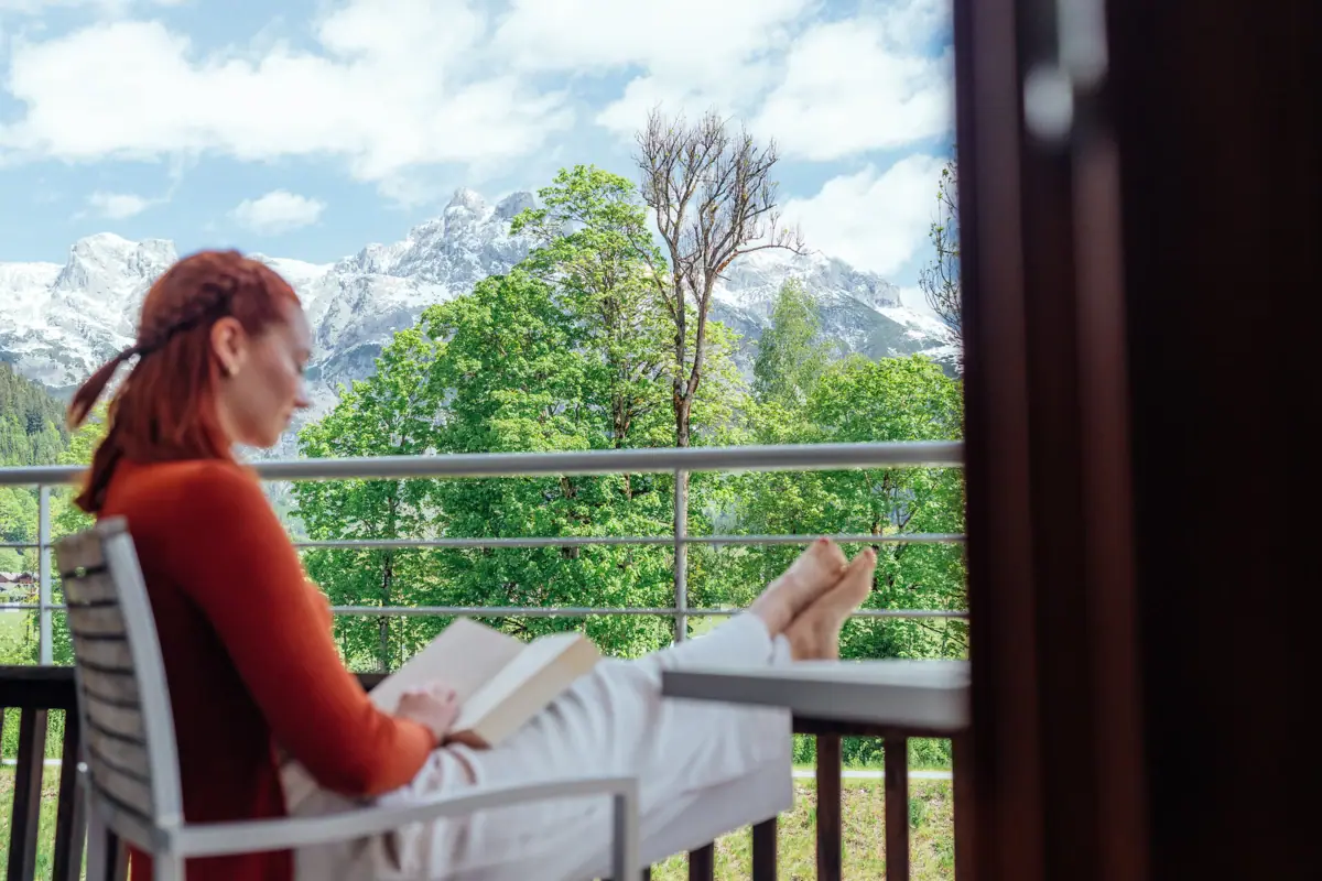 Lezen op het balkon Een vrouw zit op een balkon en leest een boek.