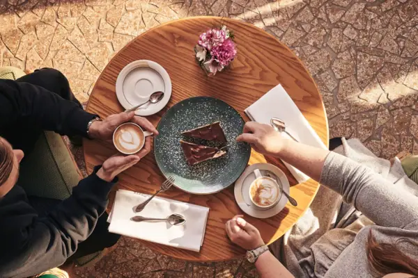 Eine Gruppe von Menschen sitzt an einem Tisch mit Kaffee und Kuchen.