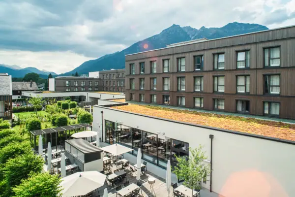Terras Een gebouw met een dak, tafels en stoelen buiten onder een bewolkte hemel.
