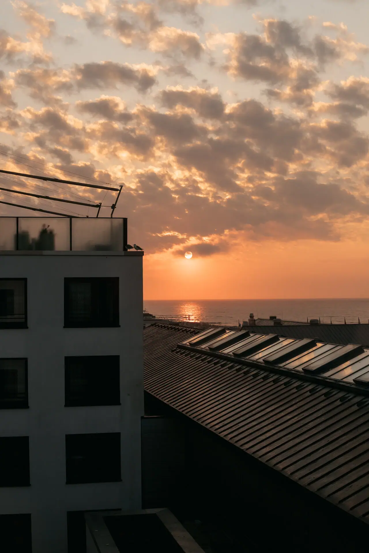 Een gebouw met een dak voor een zonsondergang.