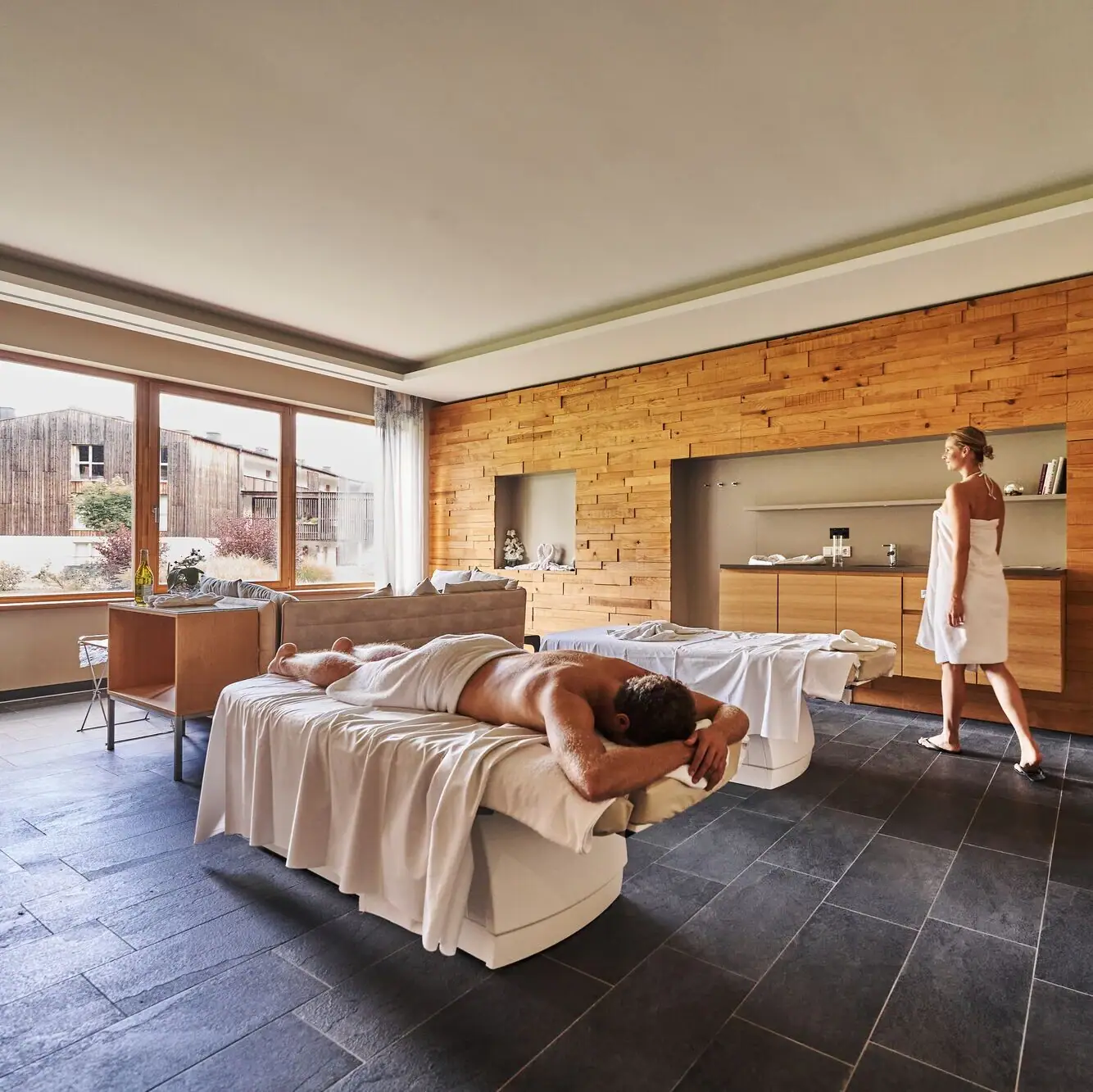 Een man ligt op een bank terwijl een vrouw achter hem staat.