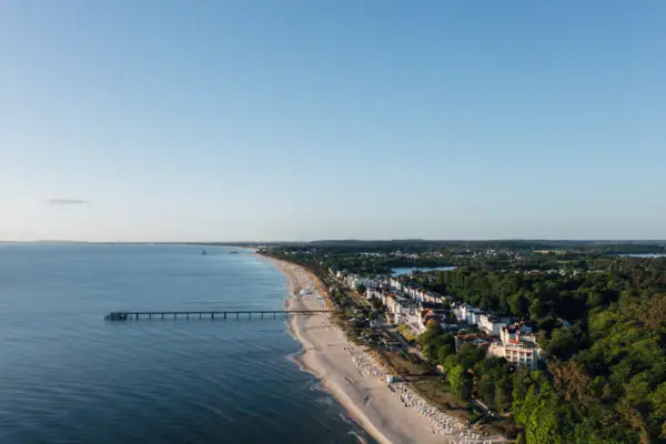 Strand met een pier en gebouwen op de achtergrond.