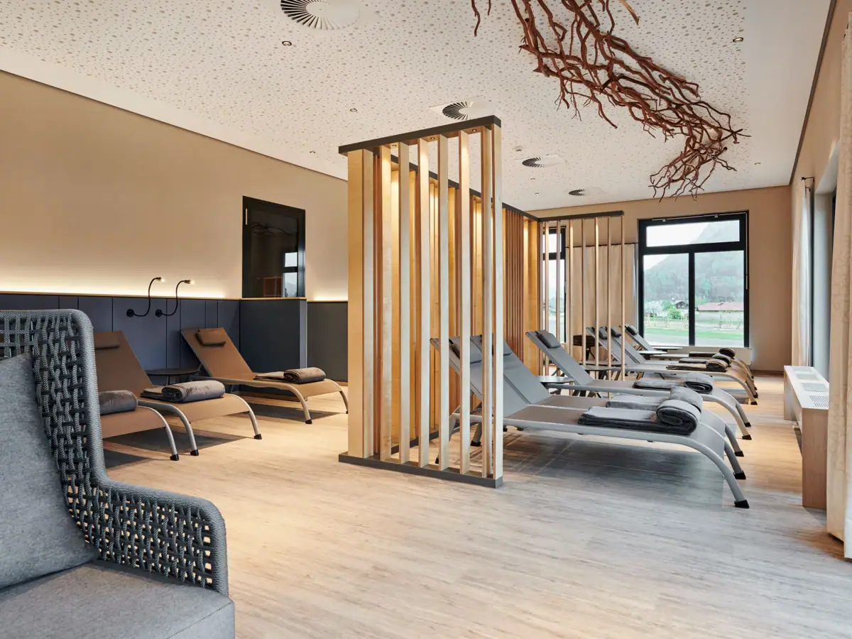 Ontspanningsruimte in het saunalandschap Een kamer met loungestoelen en een houten structuur.